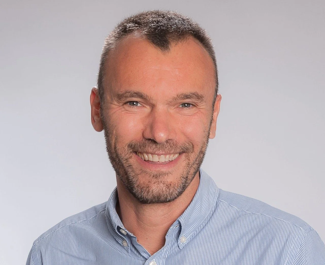 A smiling man with short hair and a beard