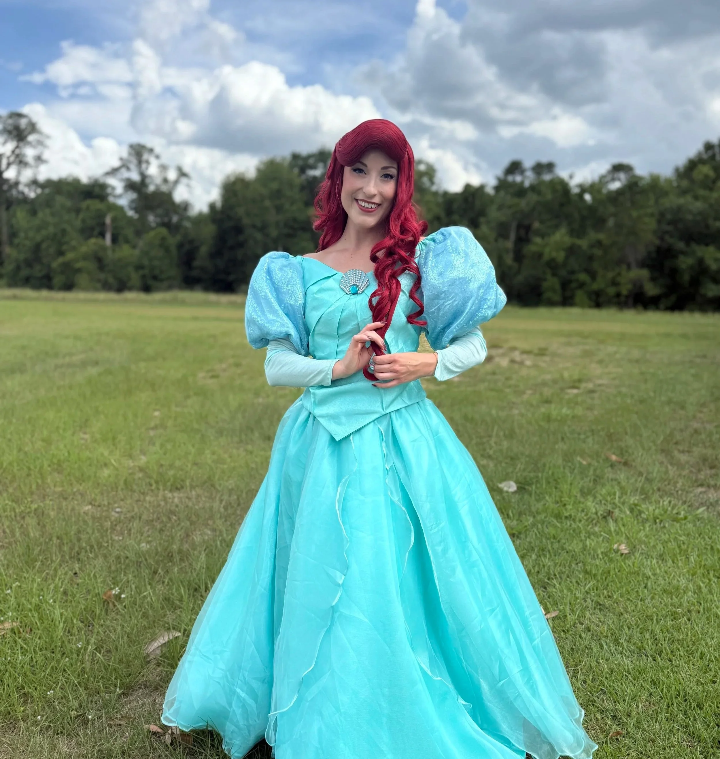 Princess Ariel from The Little Mermaid, dressed in her iconic teal gown, standing gracefully with a warm smile and flowing red hair, evoking an elegant under-the-sea royal theme perfect for a princess party.