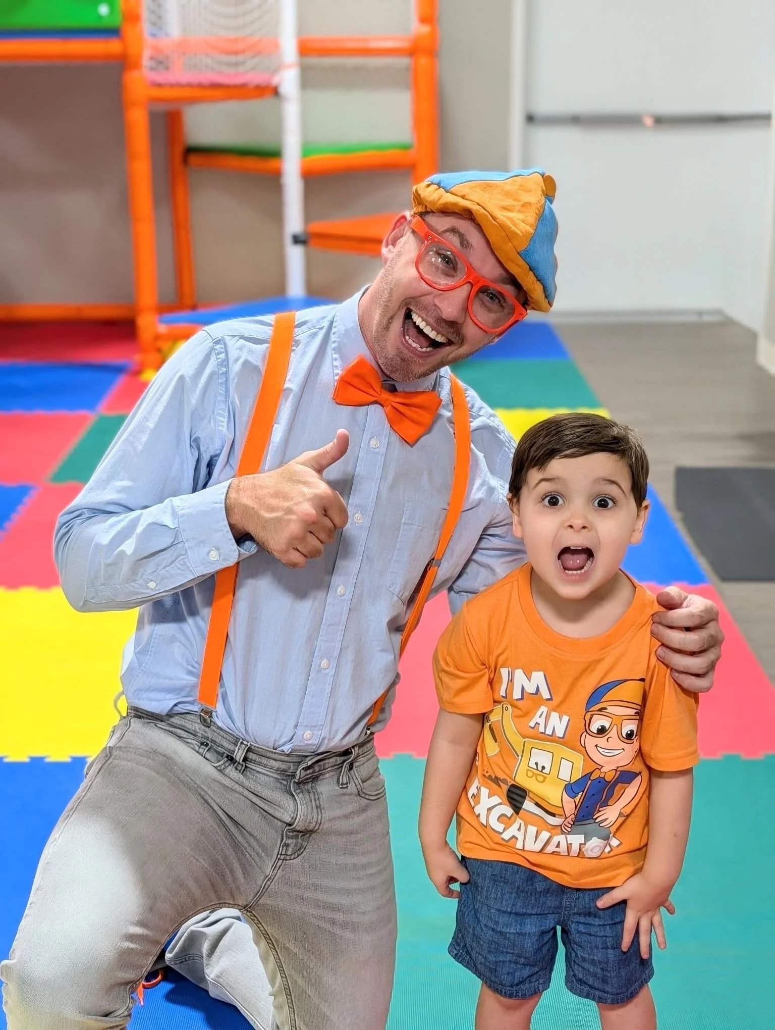 Blippi-inspired Adventure Guy posing with children at a colorful indoor kids play café