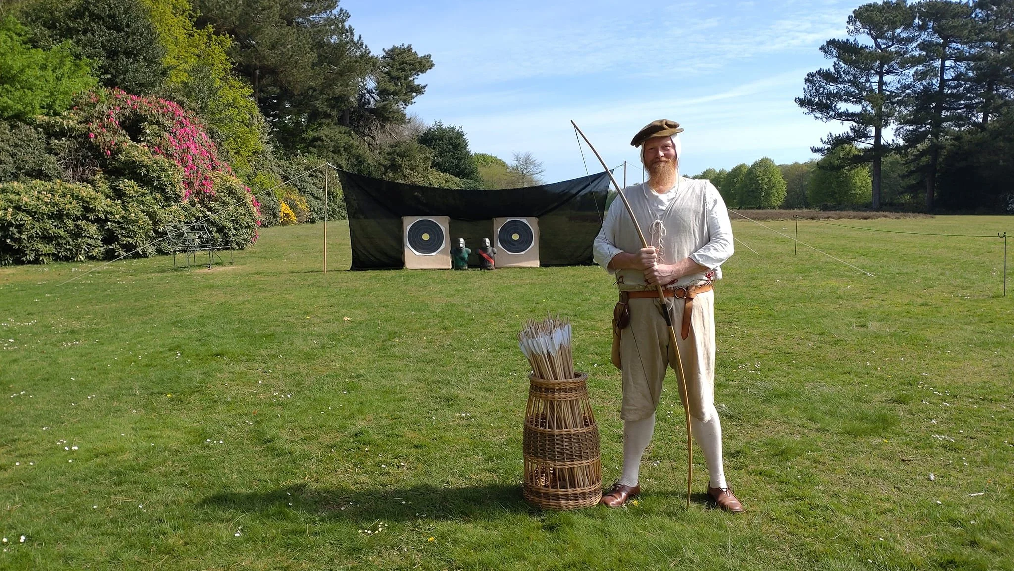 Man in authentic Tudor garb beaming with a longbow on the have-a-go archery range at Speke Hall, Liverpool