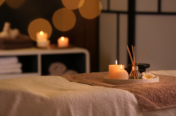 A candlelit massage table with candles and diffuser, creating a relaxing spa atmosphere.