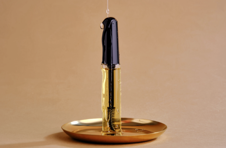 A fountain pen resting on a gold-colored ink dish with ink dripping from the nib.