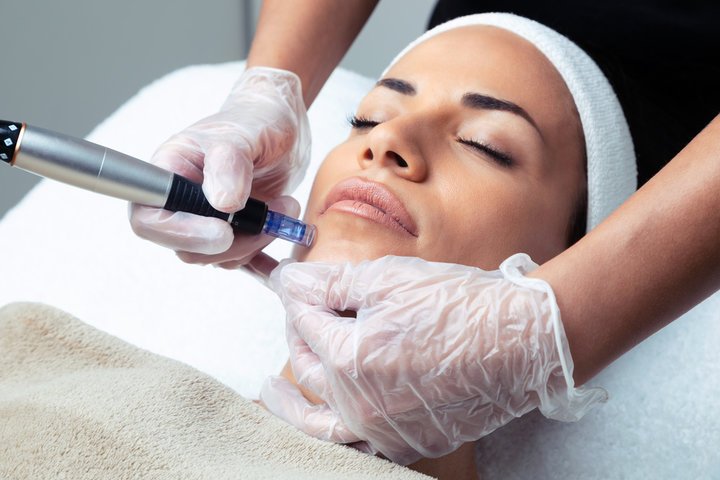 Mujer recibiendo un tratamiento facial con un aparato en un consultorio de belleza.