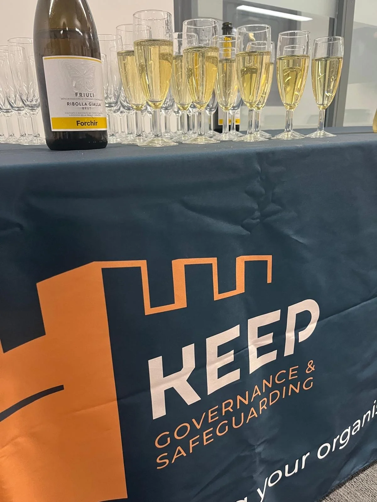 Keep Governance and Safeguarding logo on a table cloth, and champagne on the table.