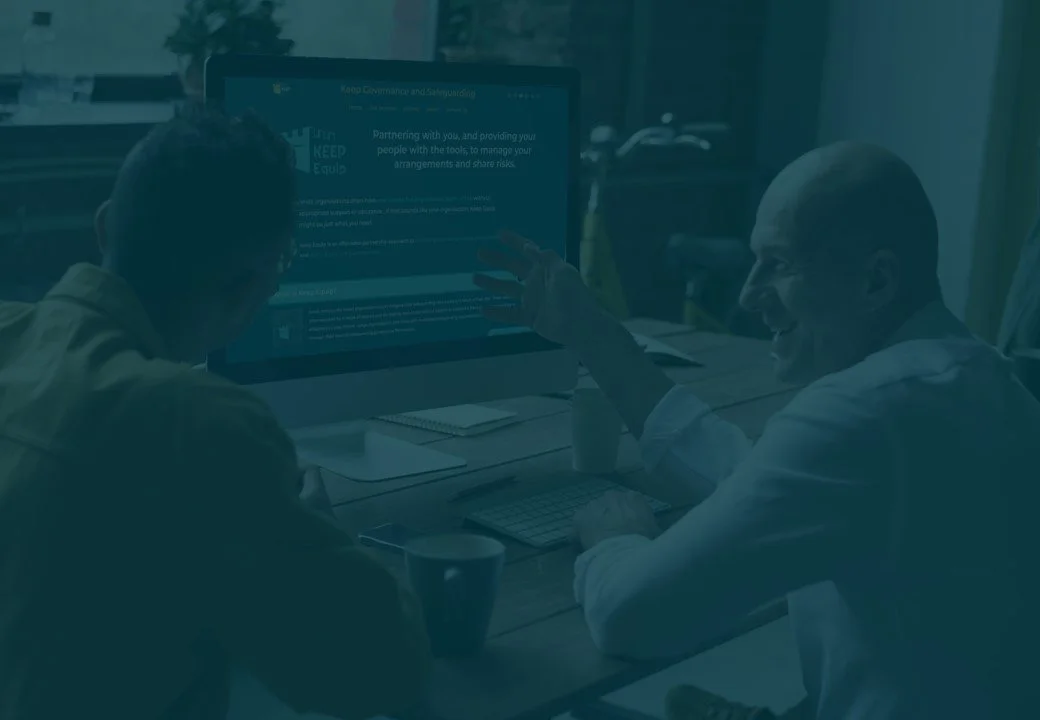Two men engaging in a discussion while looking at a computer screen in an office setting.