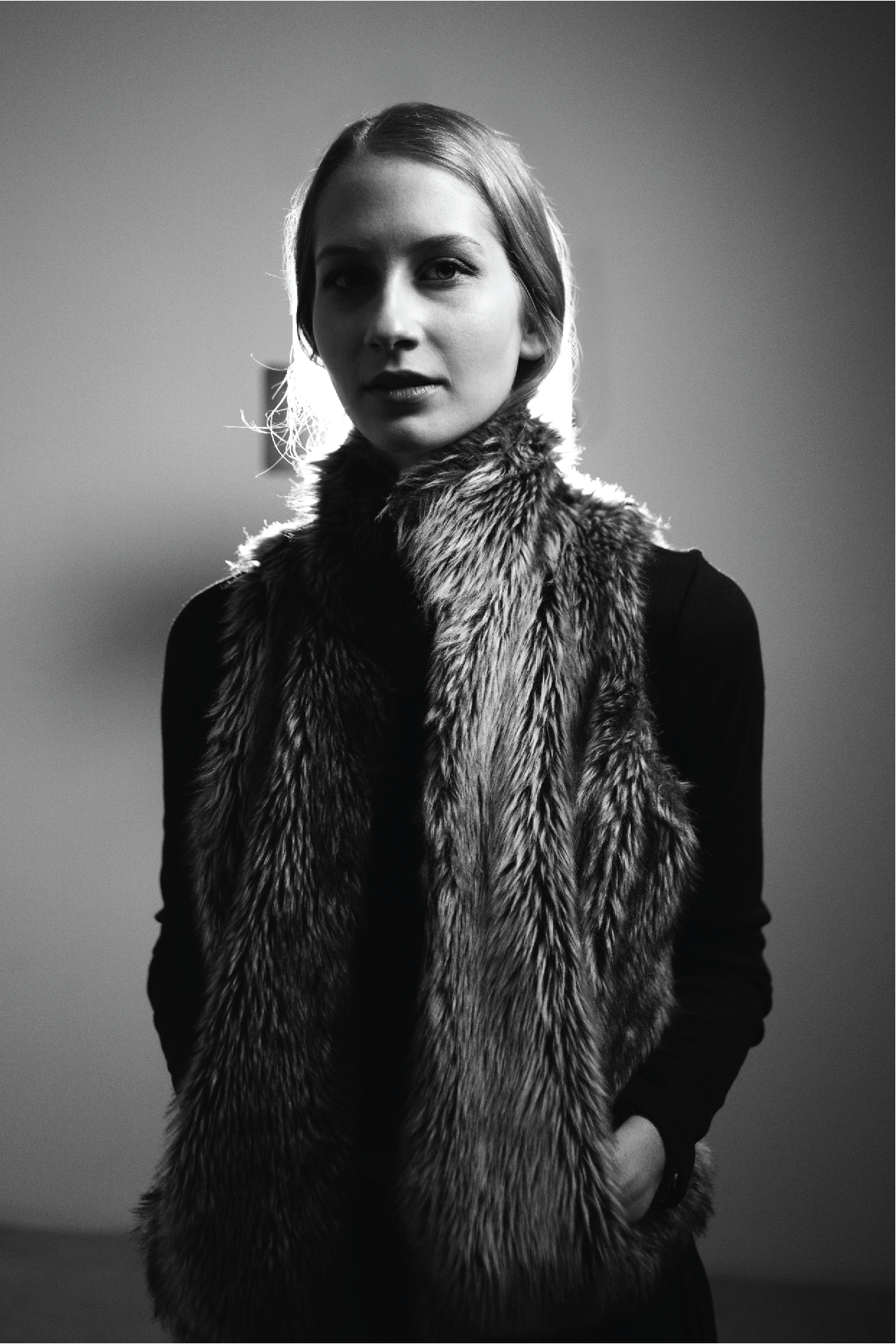 Black and white portrait of a woman with light hair wearing a fur scarf and a long-sleeved dark top, looking directly at the camera.