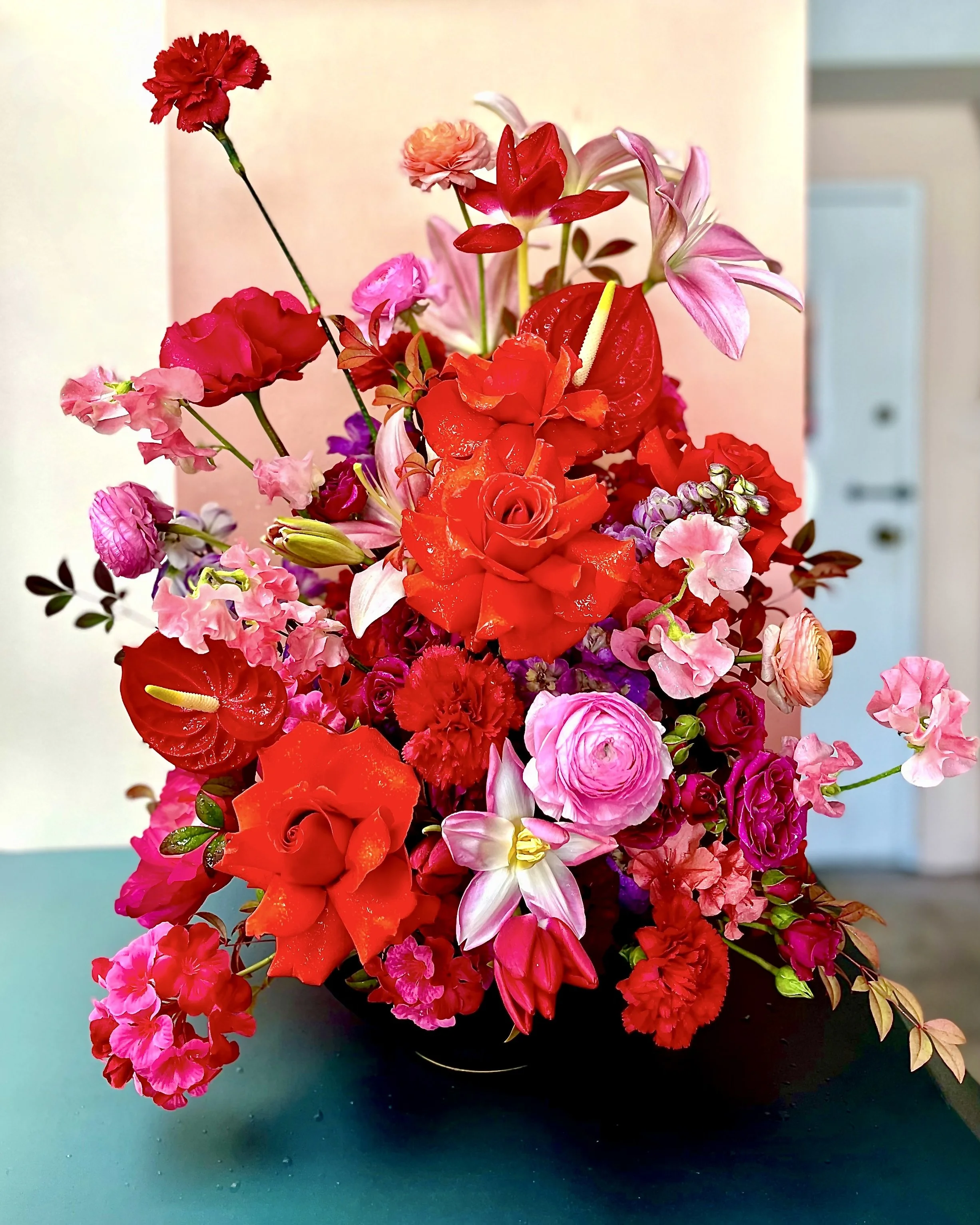 Colorful bouquet of pink, red, and purple flowers with a blue door in the background.