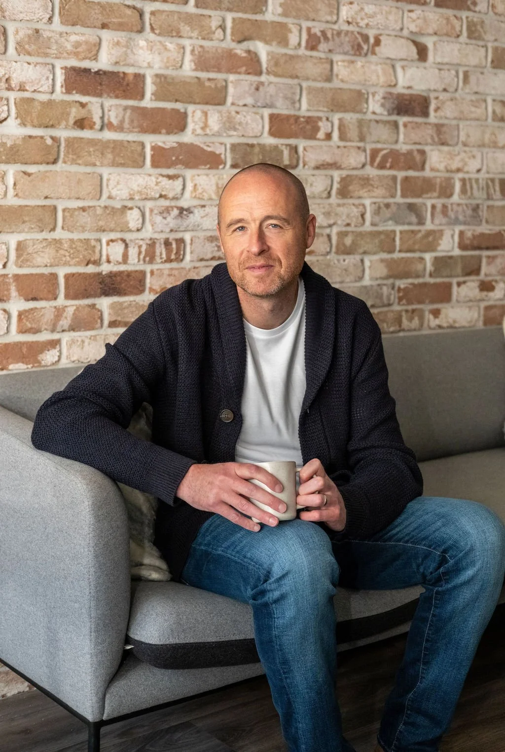 Ian O’Brien, OCD therapist in Dublin, sitting on a couch with coffee in hand and a gentle smile.