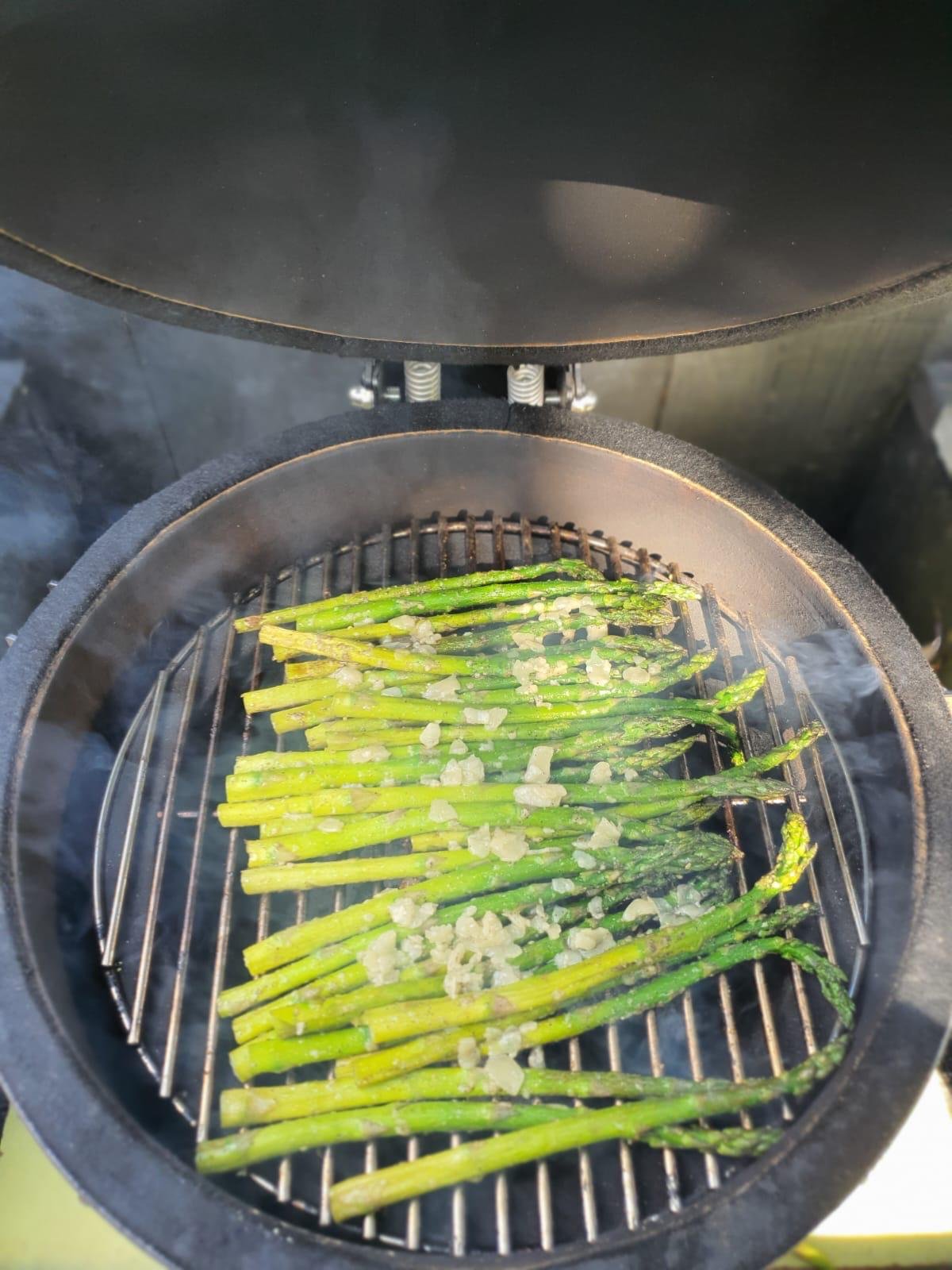 Groene asperges worden op een barbecue gegrild met knoflookboter.