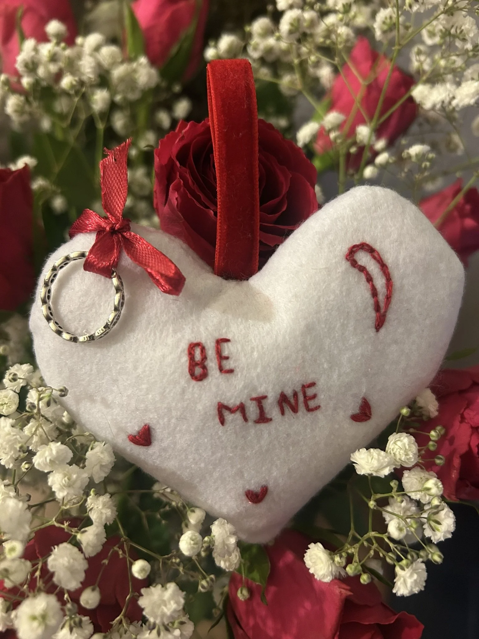 Unique handmade heart-shaped cushion ornament with ‘Be Mine’ embroidery, soft cream felt and red cotton, red satin ribbon for ring display, perfect for proposals or special romantic occasions