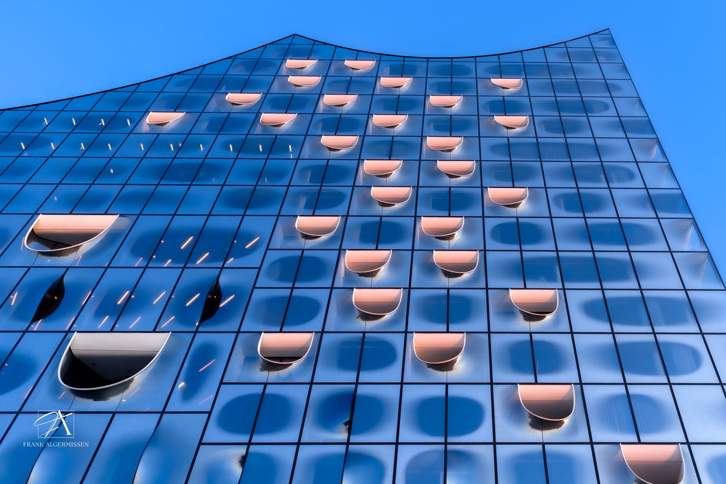 The modern glass building Hamburg Elphi with its curved window awnings and a blue sky background.