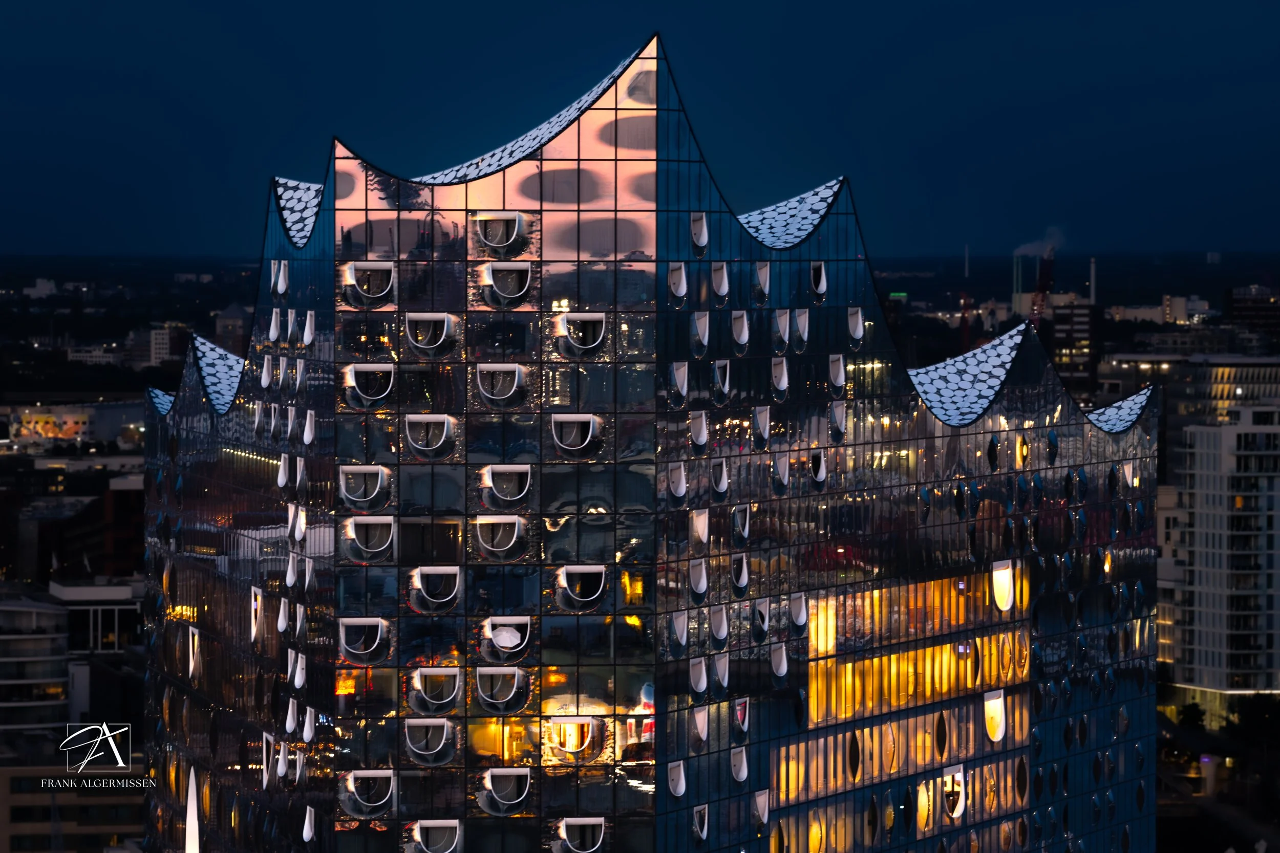 Night view of the modern Hamburg Elbphilharmonie glass building with reflective surfaces, cityscape, and dark sky.