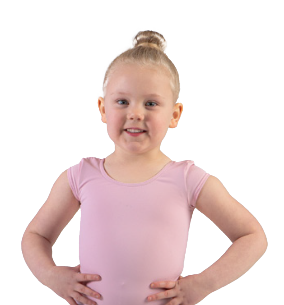 A young girl with blonde hair styled in a high bun, wearing a pink short-sleeved top, stands with her hands on her hips and smiles at the camera.