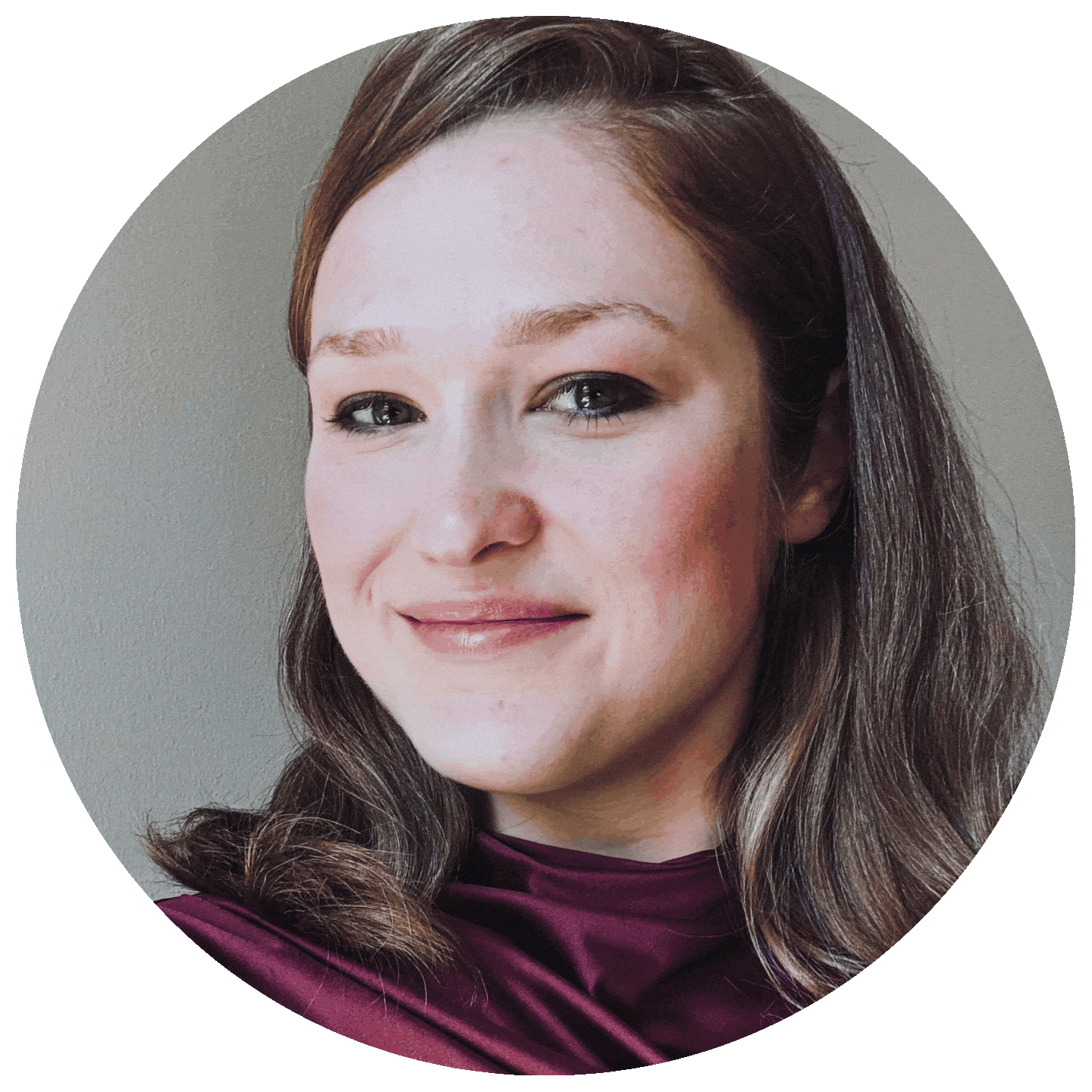 Close-up portrait of a woman with brown hair, wearing a dark maroon top, smiling softly against a neutral background.