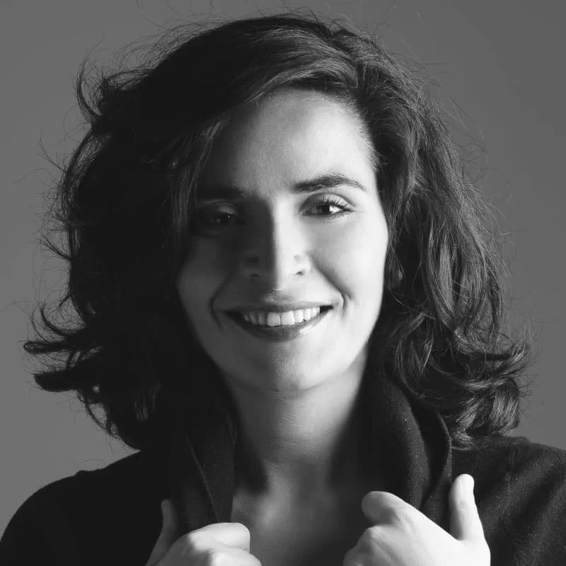 Alejandra hat schulterlanges braunes Haar und traegt ein dunkles Shirt. Das Foto ist in Schwarz-Weiss gehalten.