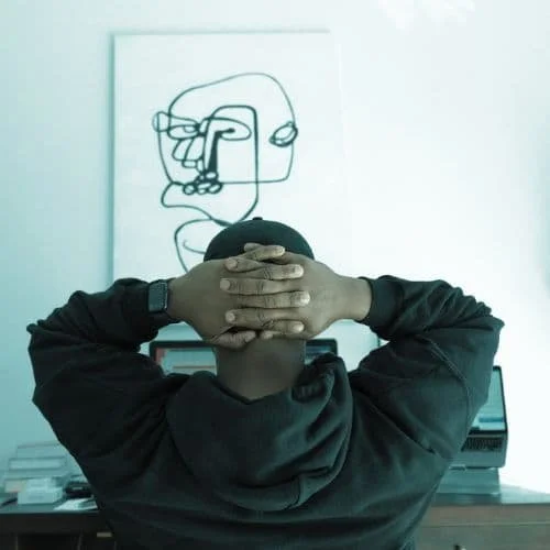 Ein Mann, der seine beiden Haender hinter dem Kopf verschraenkt