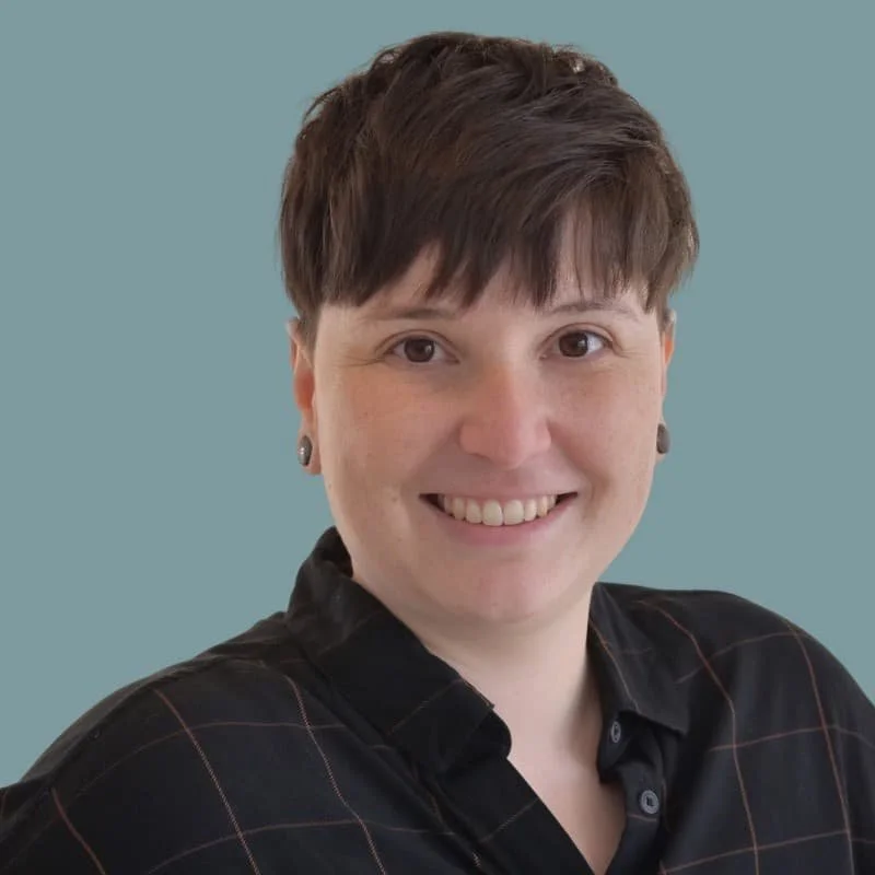 Eine Frau mit kurzen braunen Haaren und  einer schwarzen Bluse.