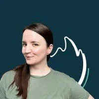 Eine Frau mit dunklem Haar, die einen grünen Pullover trägt, vor einem blauen Hintergrund mit einem weißen, stilisierten Berliner Bären im Hintergrund.