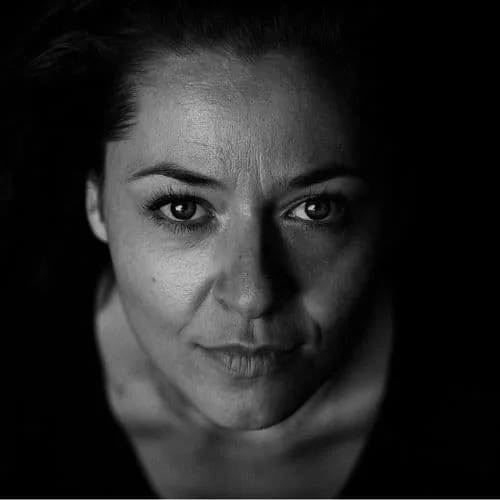 Ein Schwarz-Weiß-Porträt einer Frau, die direkt in die Kamera schaut.