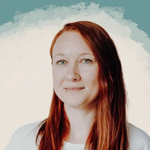 Porträt einer Frau mit langen roten Haaren vor einem hellen Hintergrund.