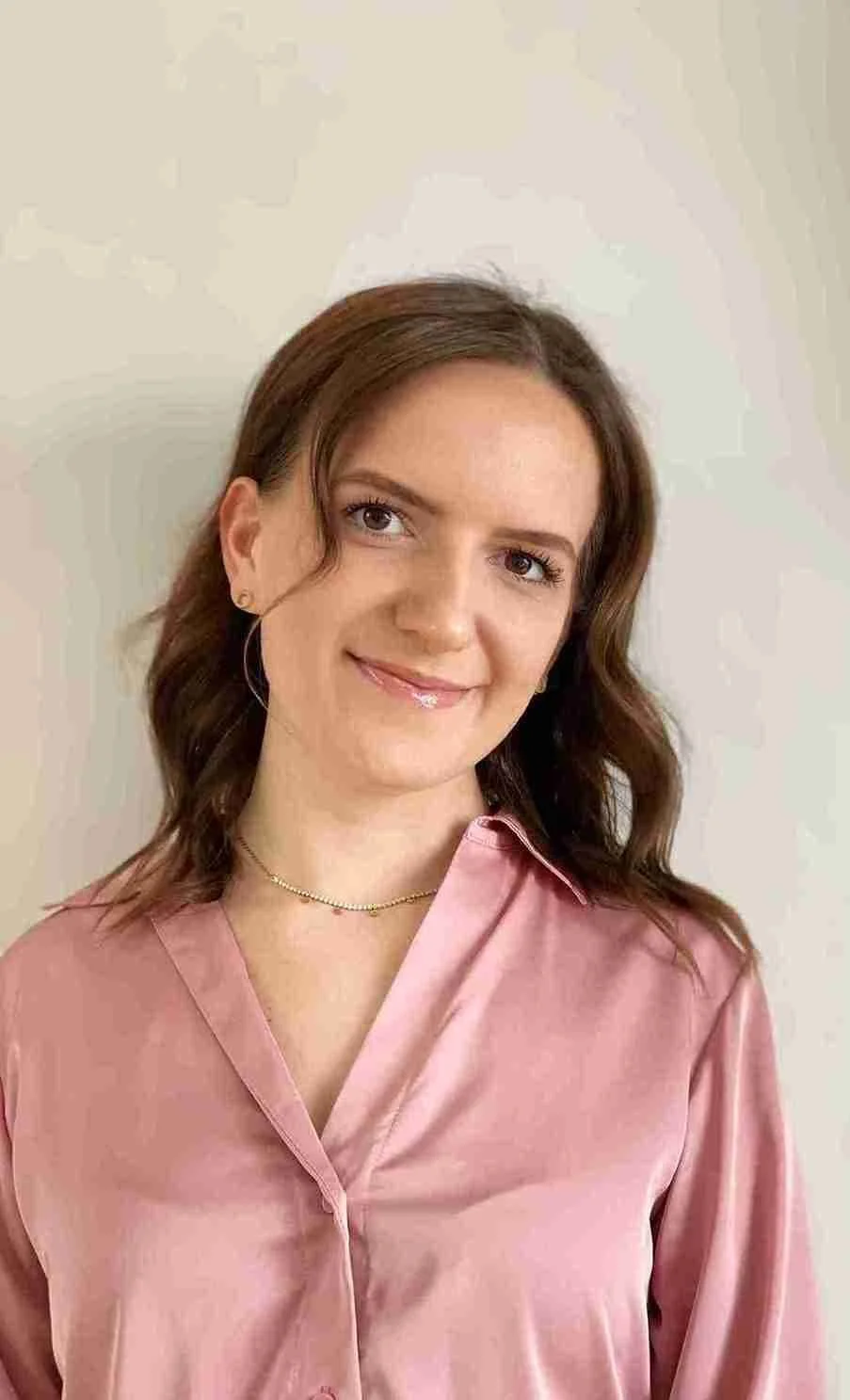 Katharina hat braunes langes Haar und sie traegt eine Rosa Bluse