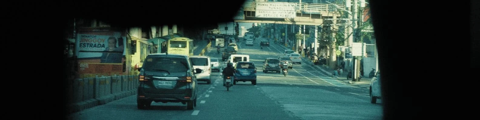 Straßenansicht mit Autos, Fahrrädern und öffentlichen Verkehrsmitteln in einer urbanen Gegend.