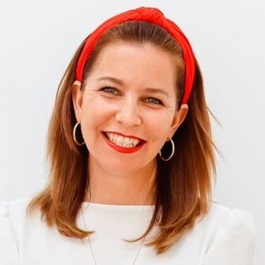 Julia hat roetliches langes Haar, einen roten Haarreif  und traegt ein weisses Shirt.