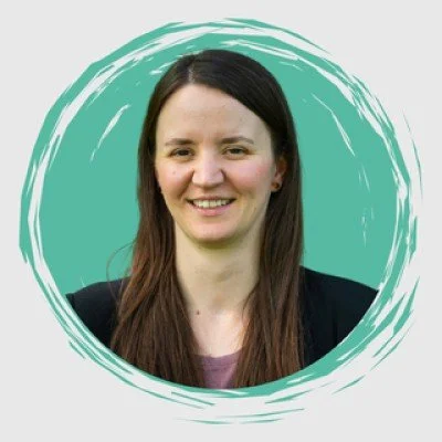 Porträt einer lächelnden Frau mit braunen Haaren vor einem grünen Hintergrund in einem kreisförmigen Rahmen.