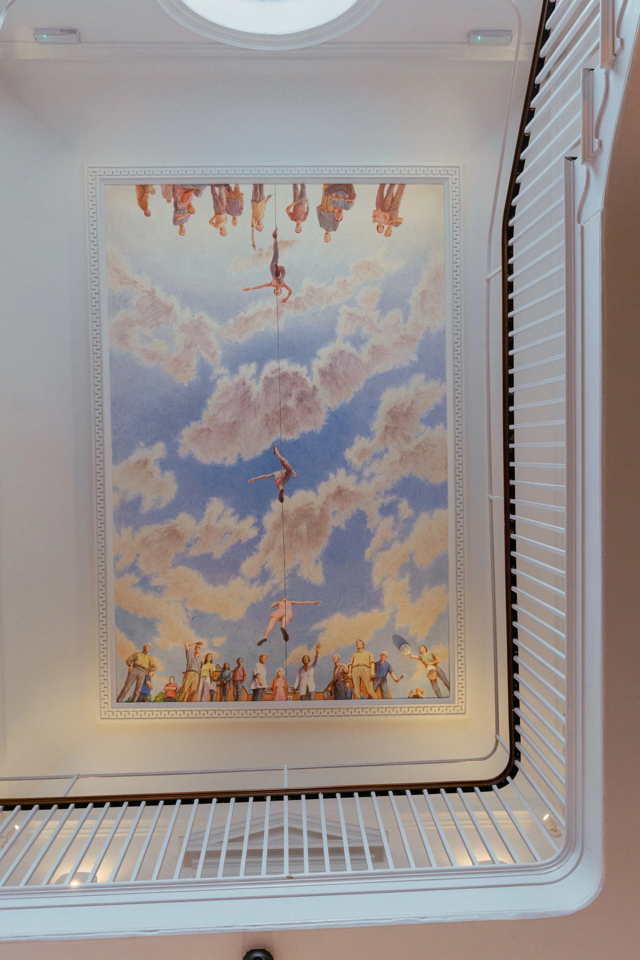 Ceiling mural depicting acrobats performing aerial acts, with people watching below, painted against a sky with clouds.