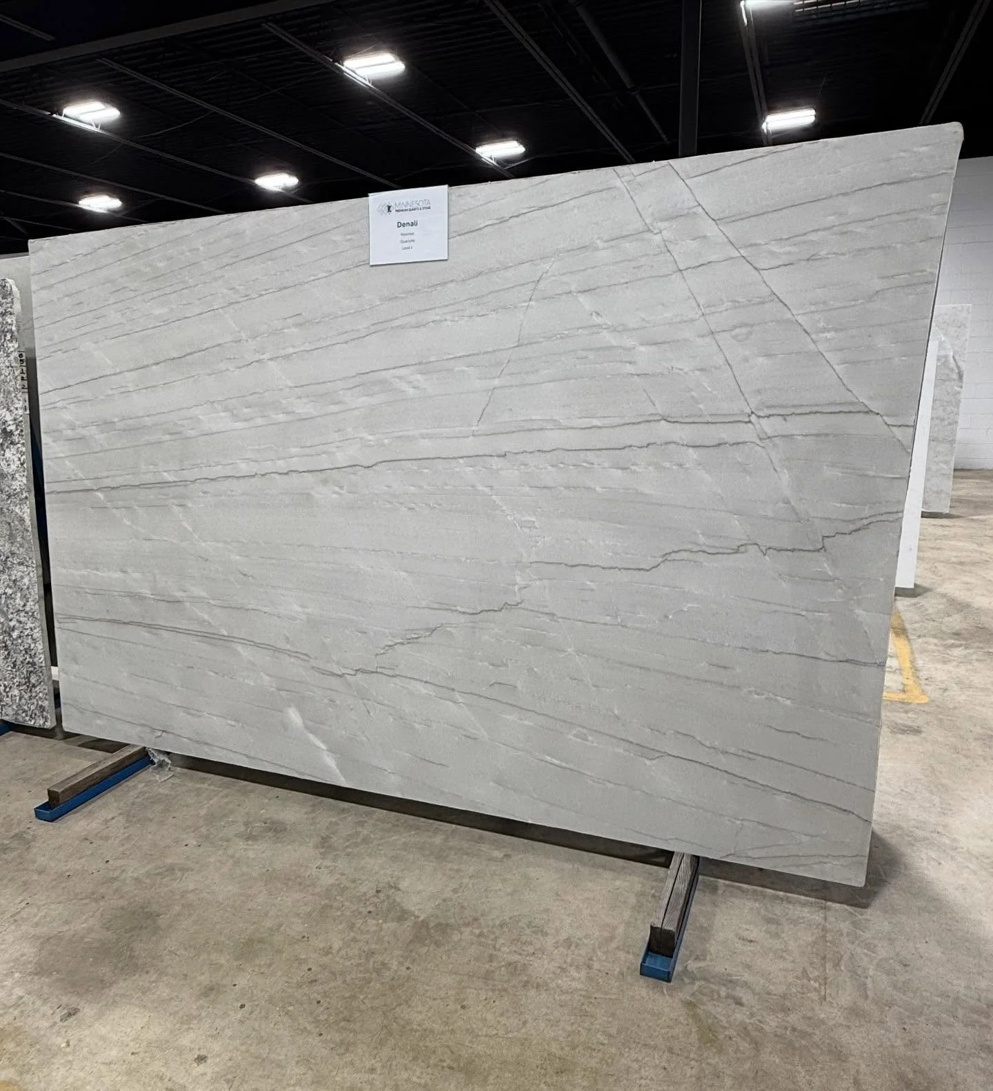 🚨New Arrival🚨 Denali Quartzite - A stunning natural stone quarried from Brazil that features a soft white background with gentle gray movement. This premium stone is prized for its strength and sophisticated look. Come take a look! 👀