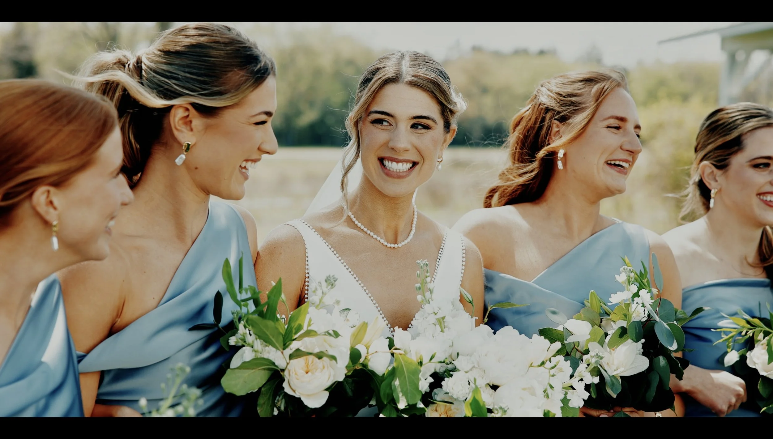 Bridesmaids smiling with bouquets in a cinematic Michigan wedding film still