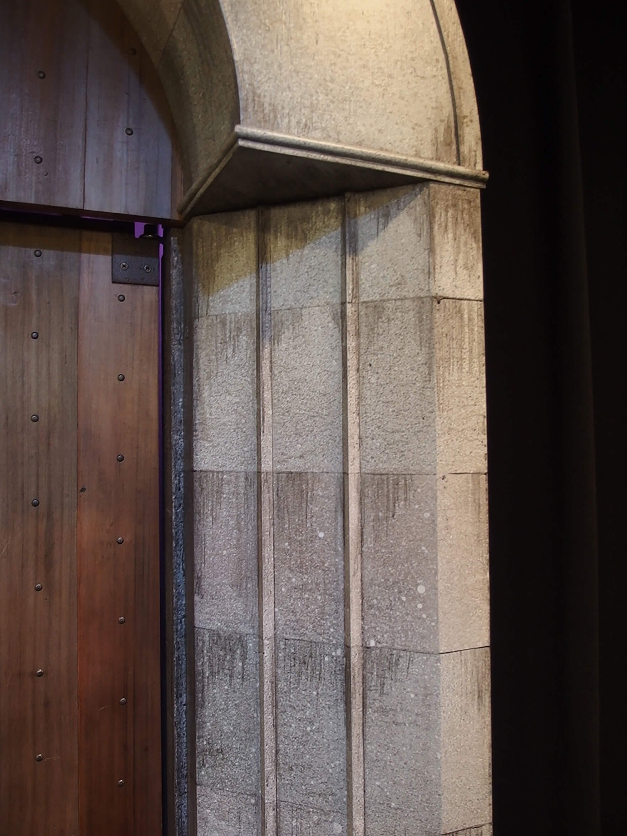 Close-up of a stone and wood doorway arch with a black background.