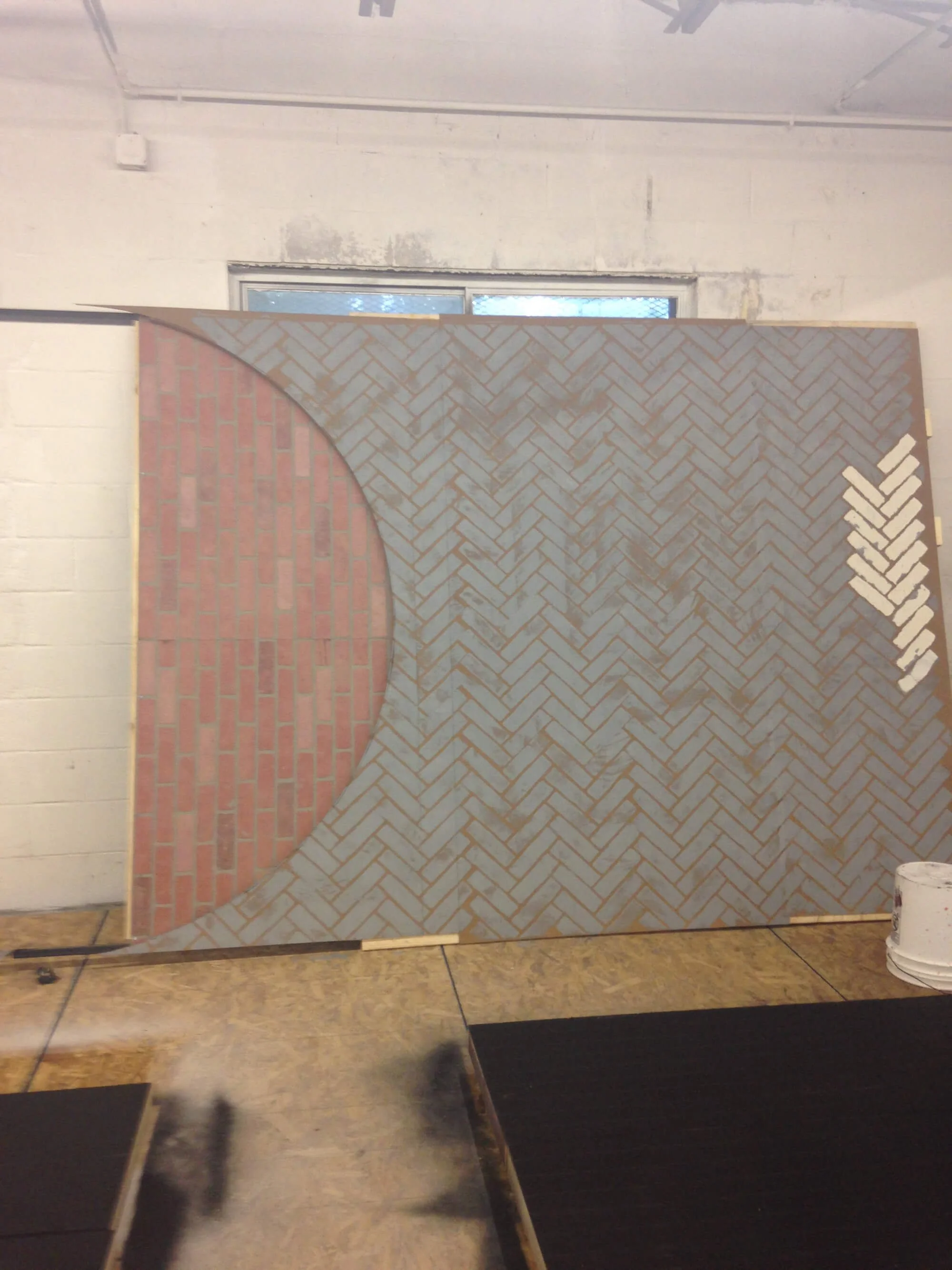A large display board showing a pattern of red brick and gray herringbone-patterned tiles.
