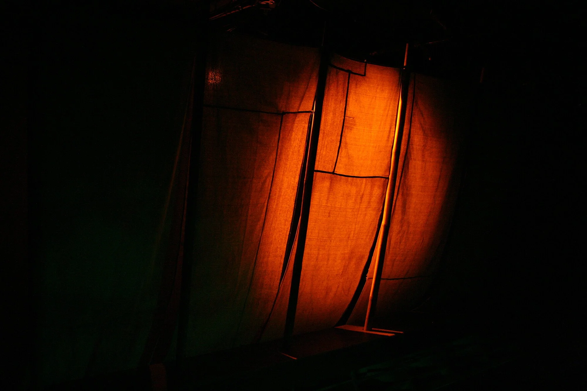 A glowing orange paper lantern against a dark background, turned on and illuminated from within.