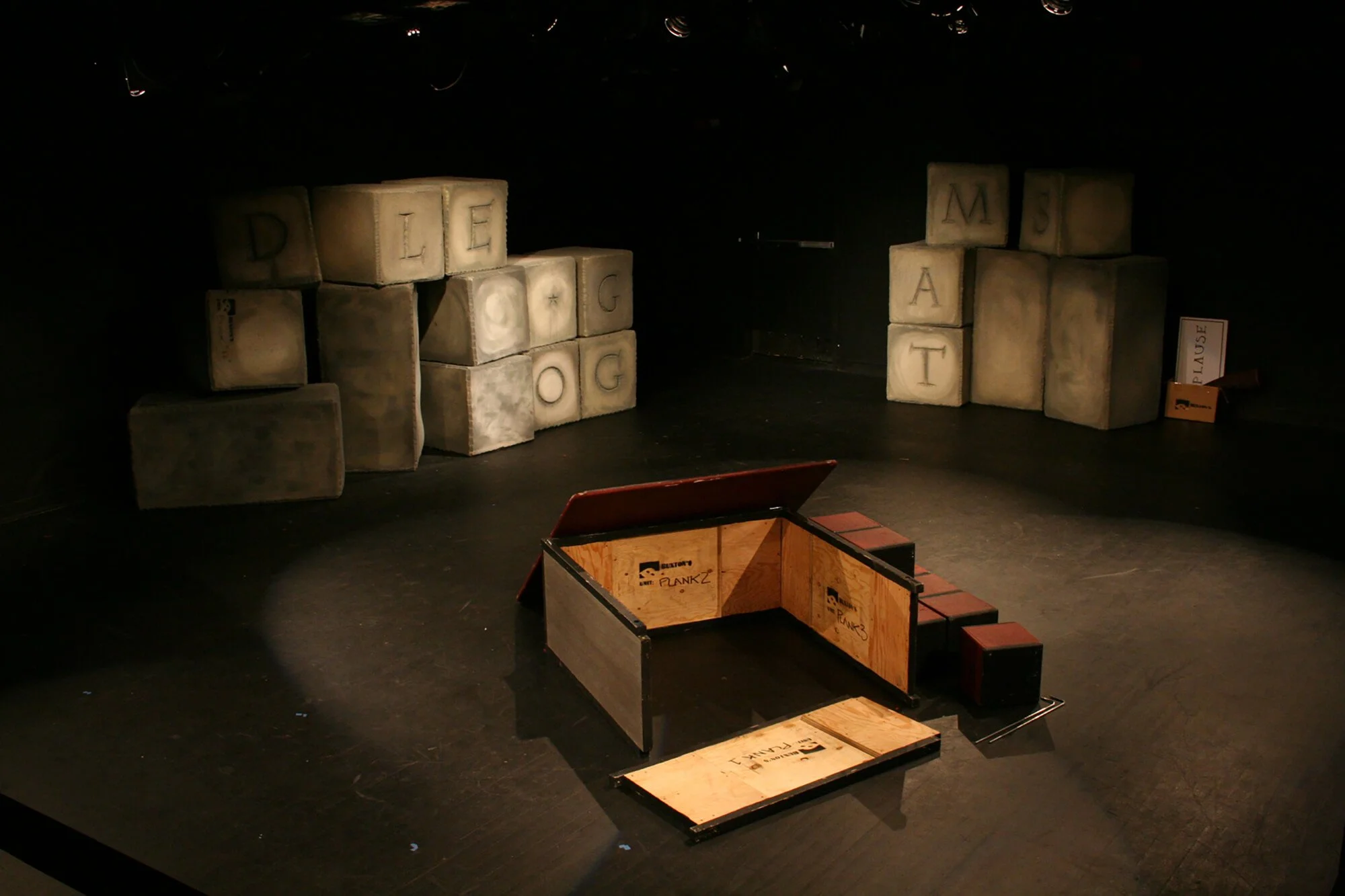 Stage with large fabric blocks spelling 'DILE' and 'MATT' and an open wooden box and smaller blocks on the floor.
