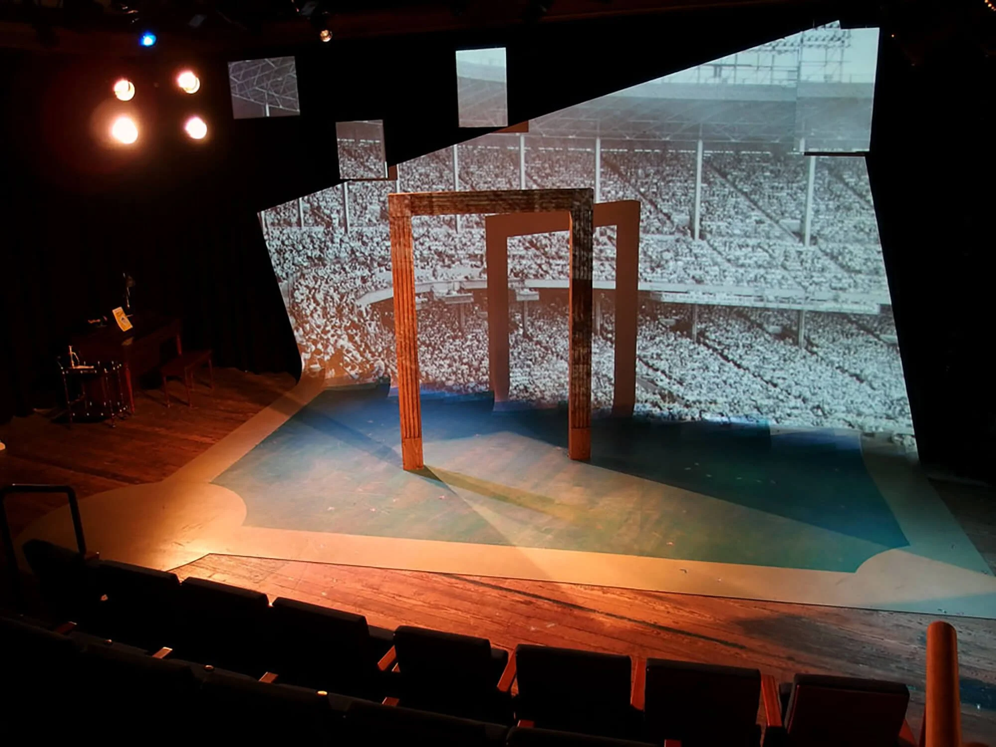 Stage with wooden arch and large black-and-white print of a stadium in the background.