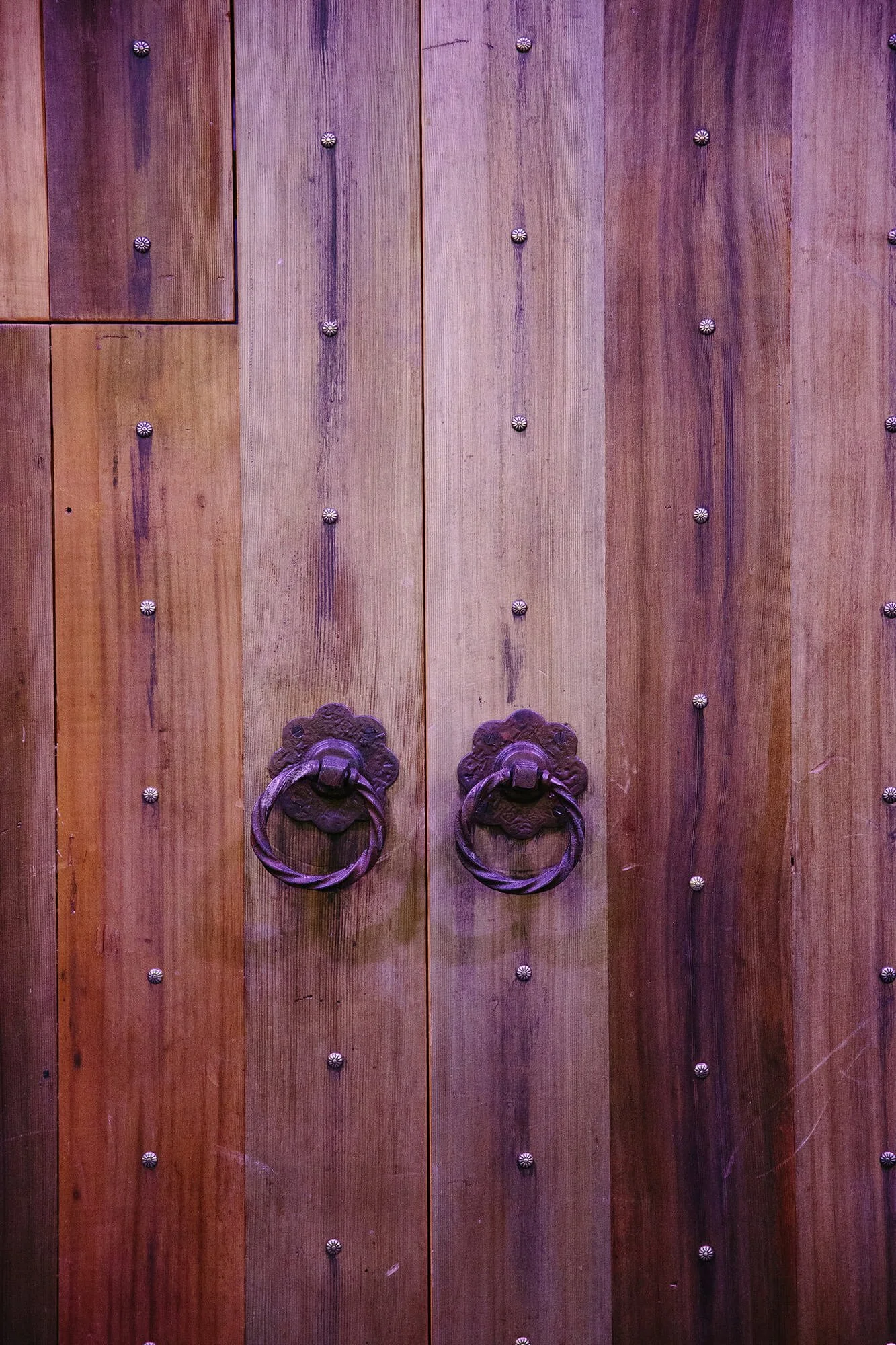 Wooden double door with metal handles and decorative studs.