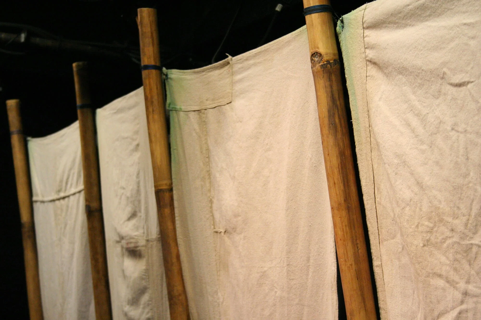 Close-up of fabric partitions supported by bamboo poles.