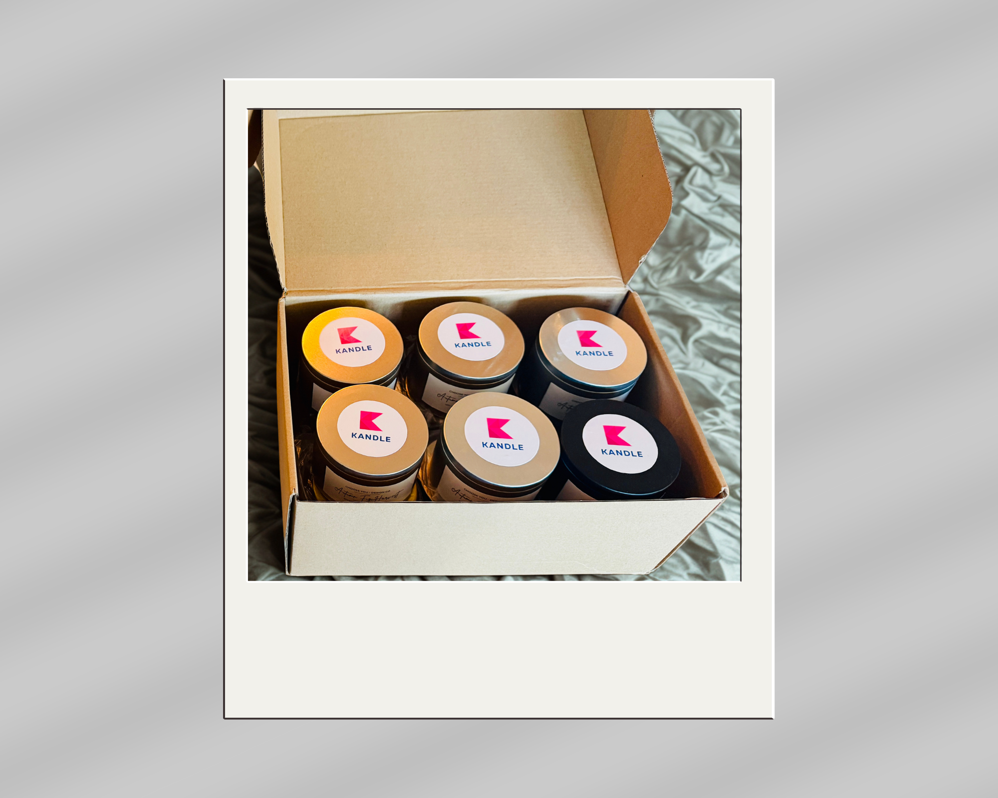 A box containing six candles with labels displaying the brand name 'KANDLE' and a pink logo.
