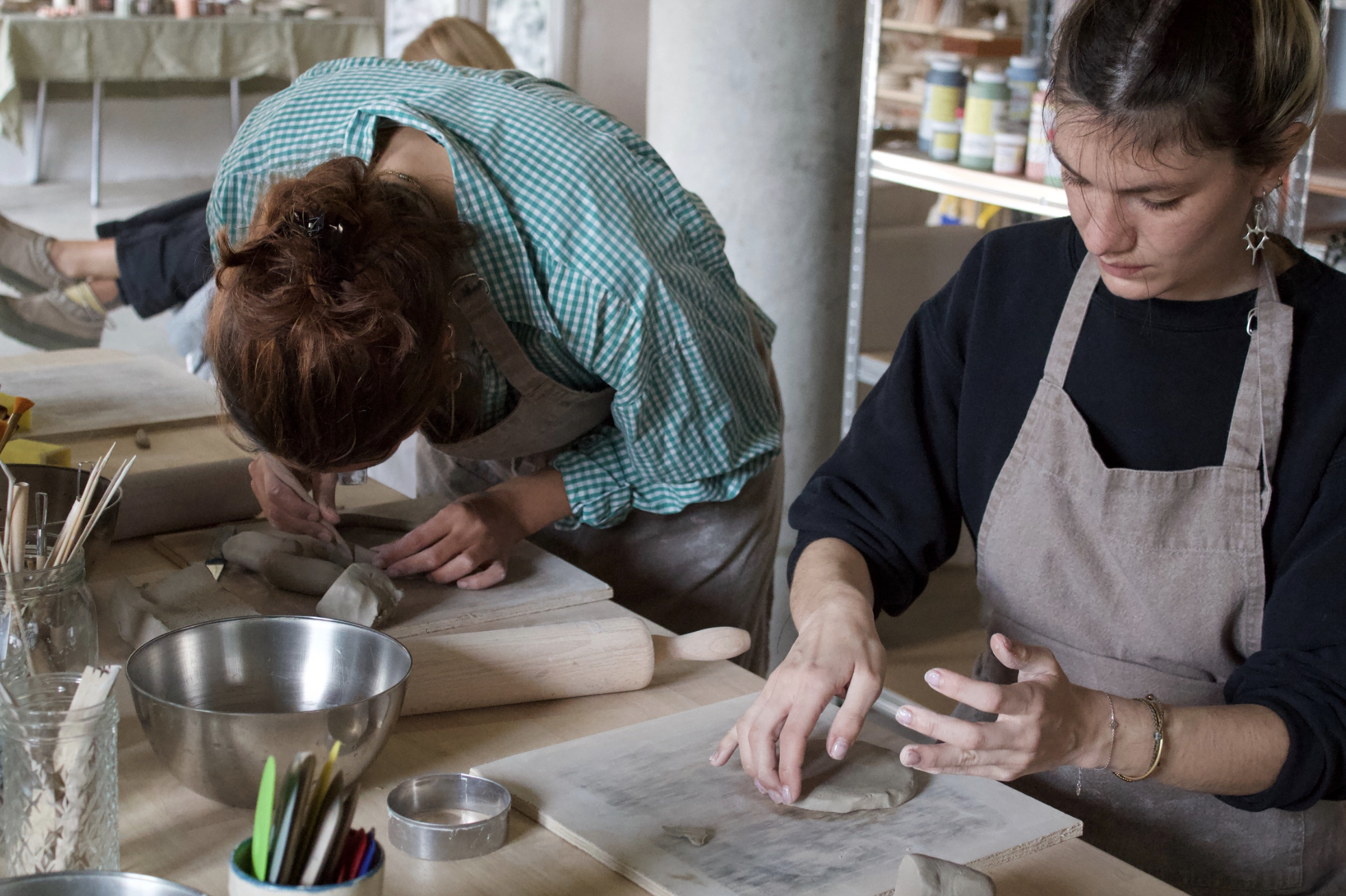 Deux femmes qui font de la poterie dans un atelier, modelant de l'argile à la main.