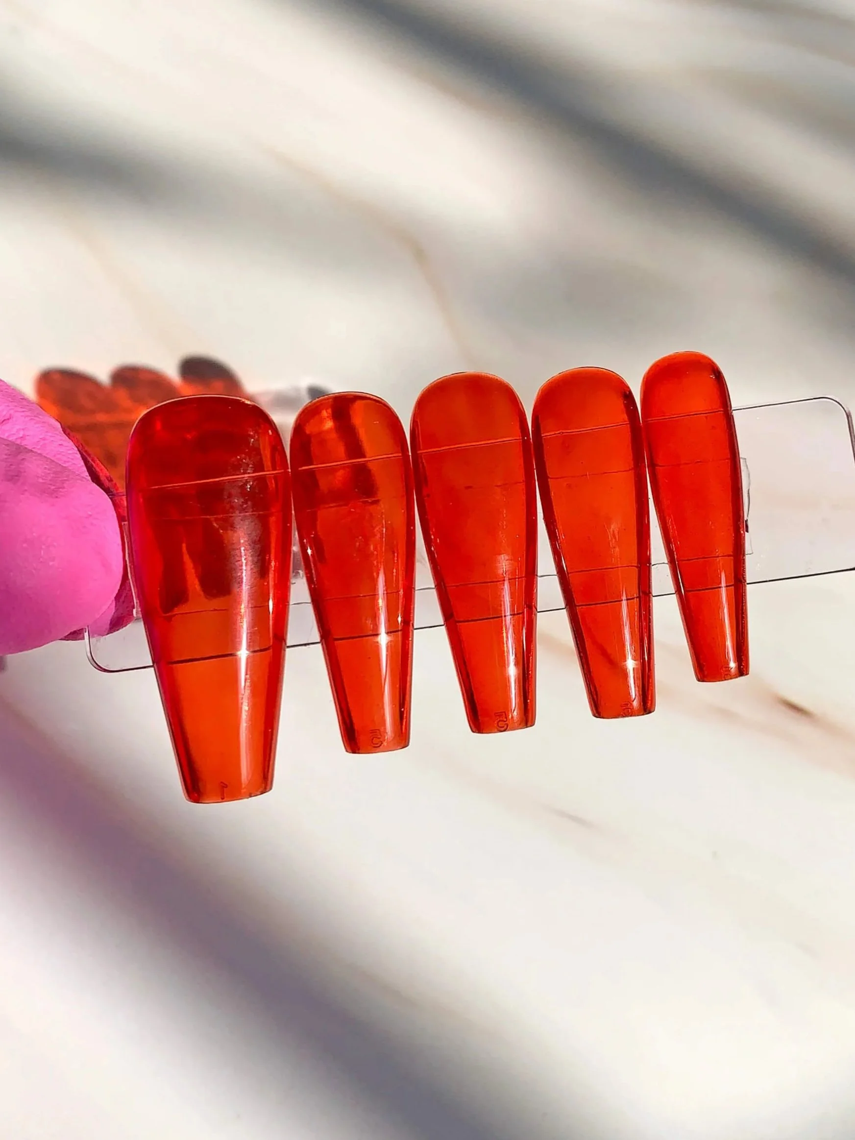 Long coffin press-on nails in bright red jelly polish.