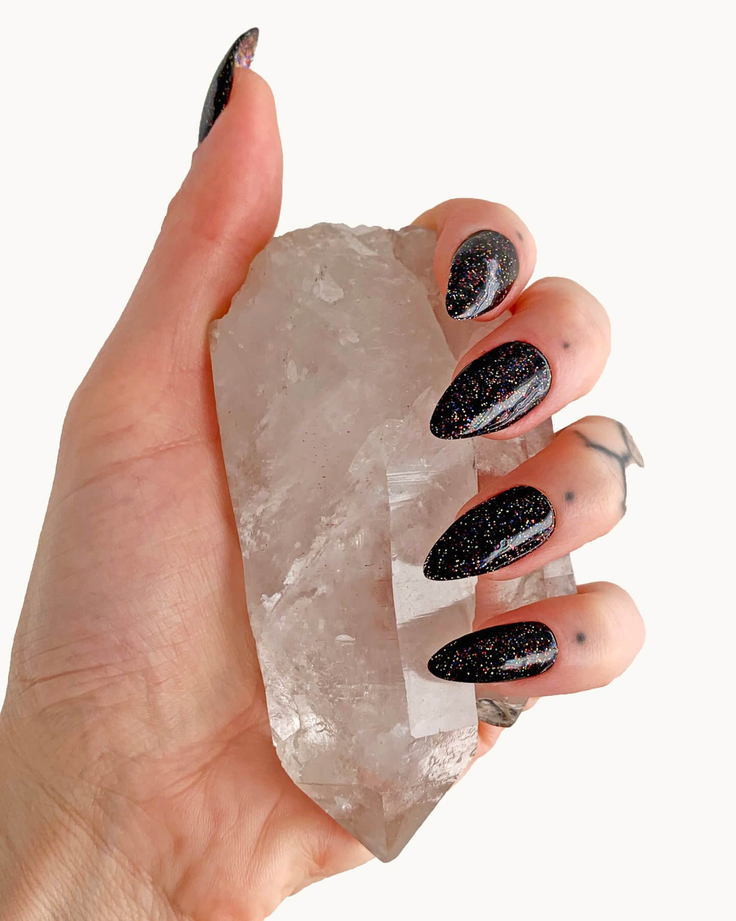 Glittery black gel polish on press-on nails in almond.