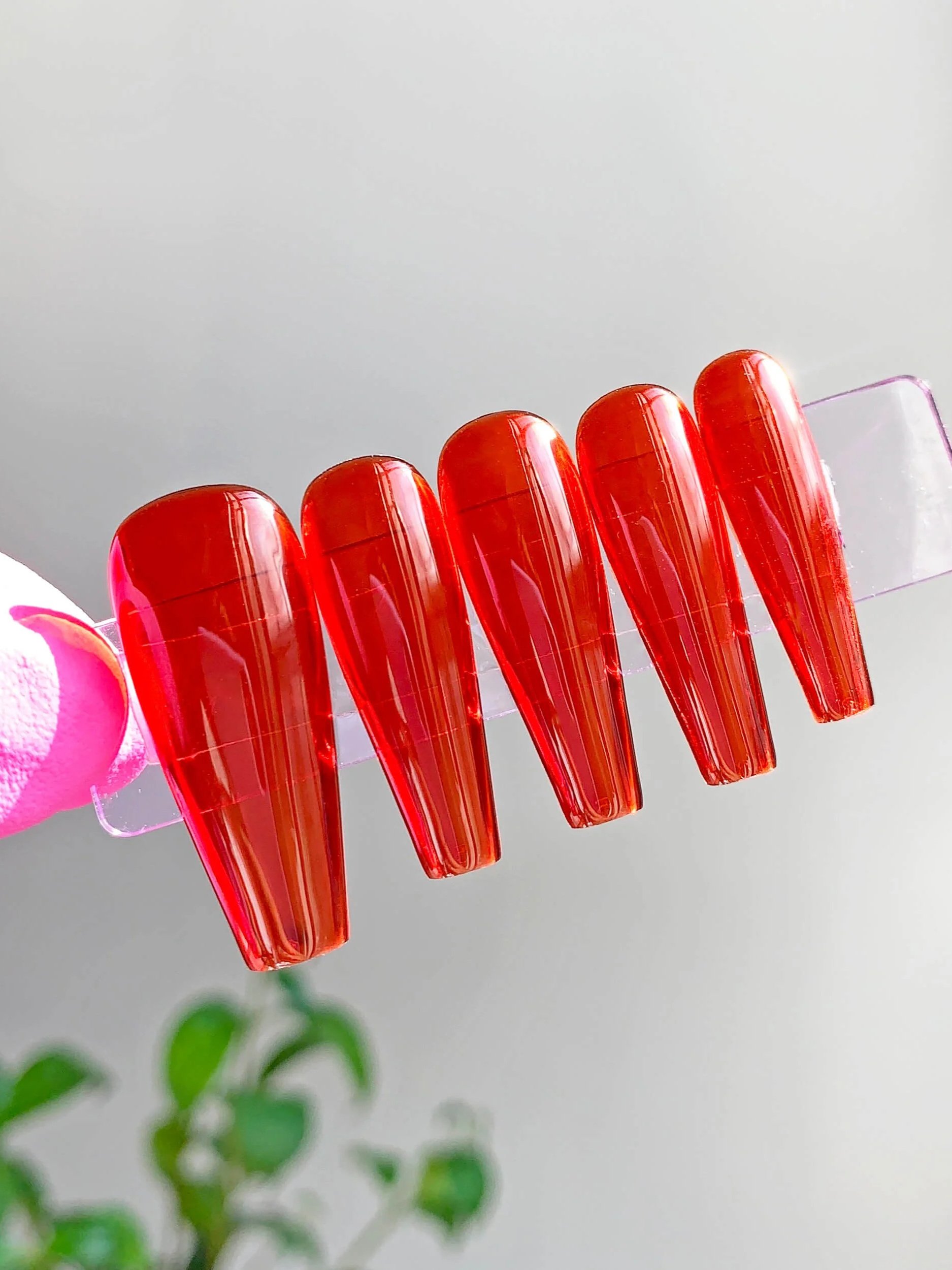 Long coffin press-on nails in red jelly gel polish.