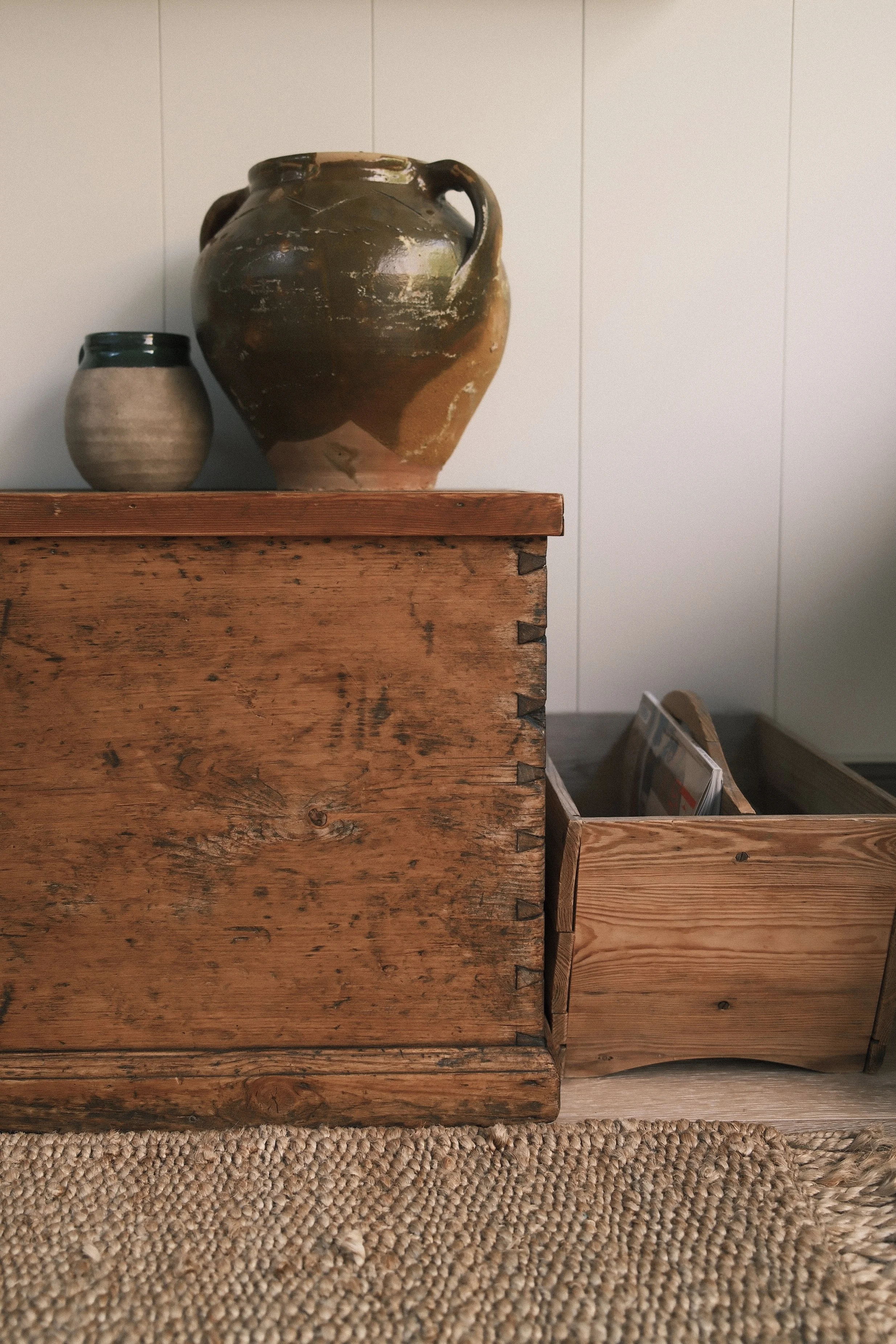 Three wooden boxes and two ceramic vases on a surface against a wall.