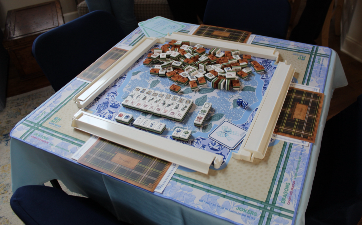 A game of Mahjong played on a table with tiles, dice, and game pieces.