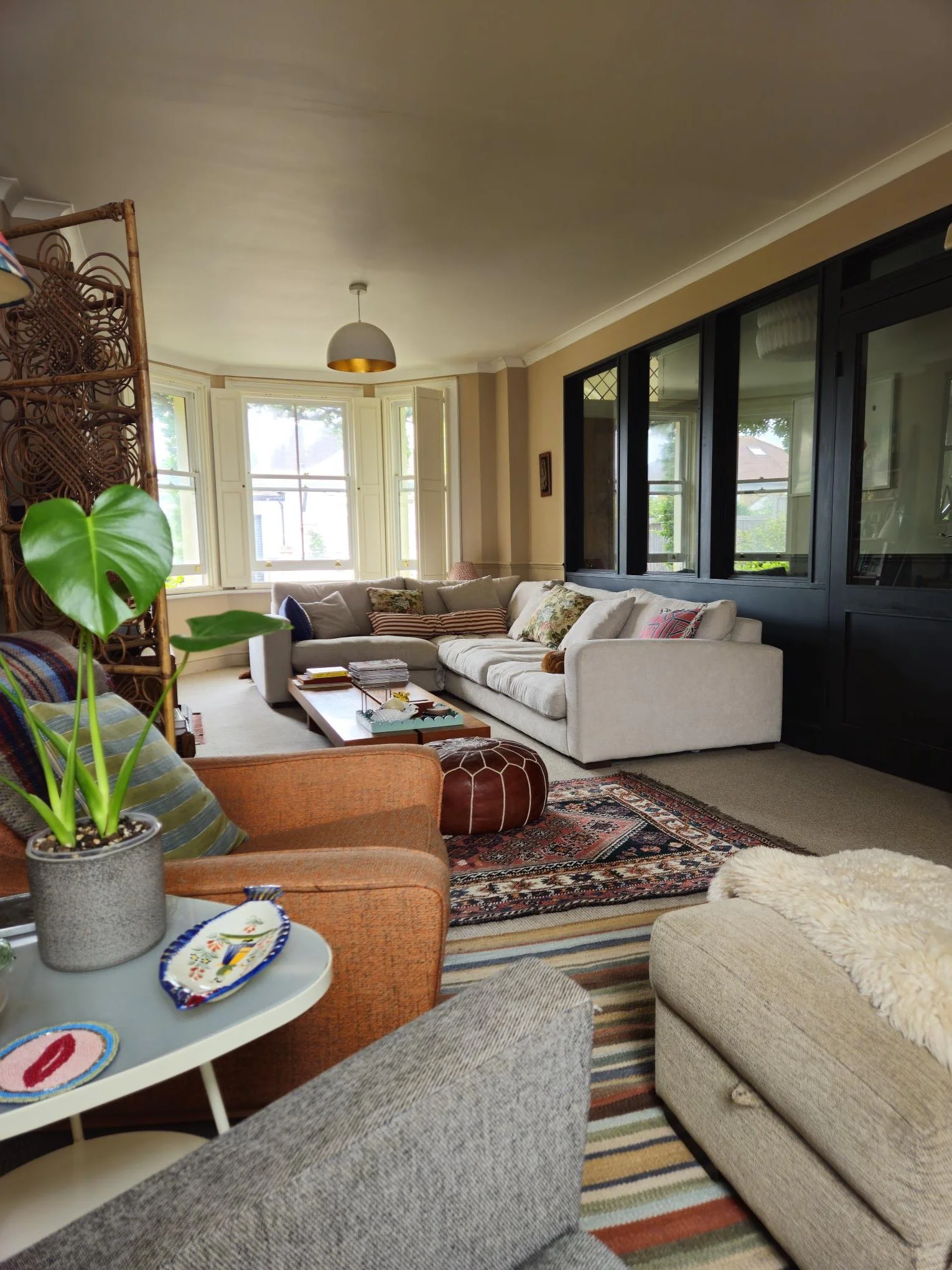 The living room is split into two key areas with 2 distinct functions - 1 to watch TV and the other to read and relax. The glass partition acts as a divider and keeps the hallway separate. The colours help support a peaceful space.