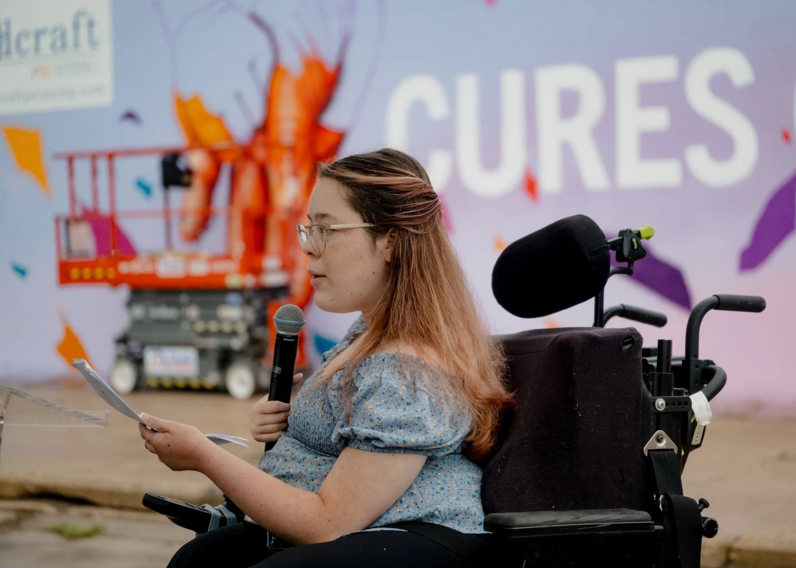 A participant speaking in front of the Cures Can’t Wait mural.