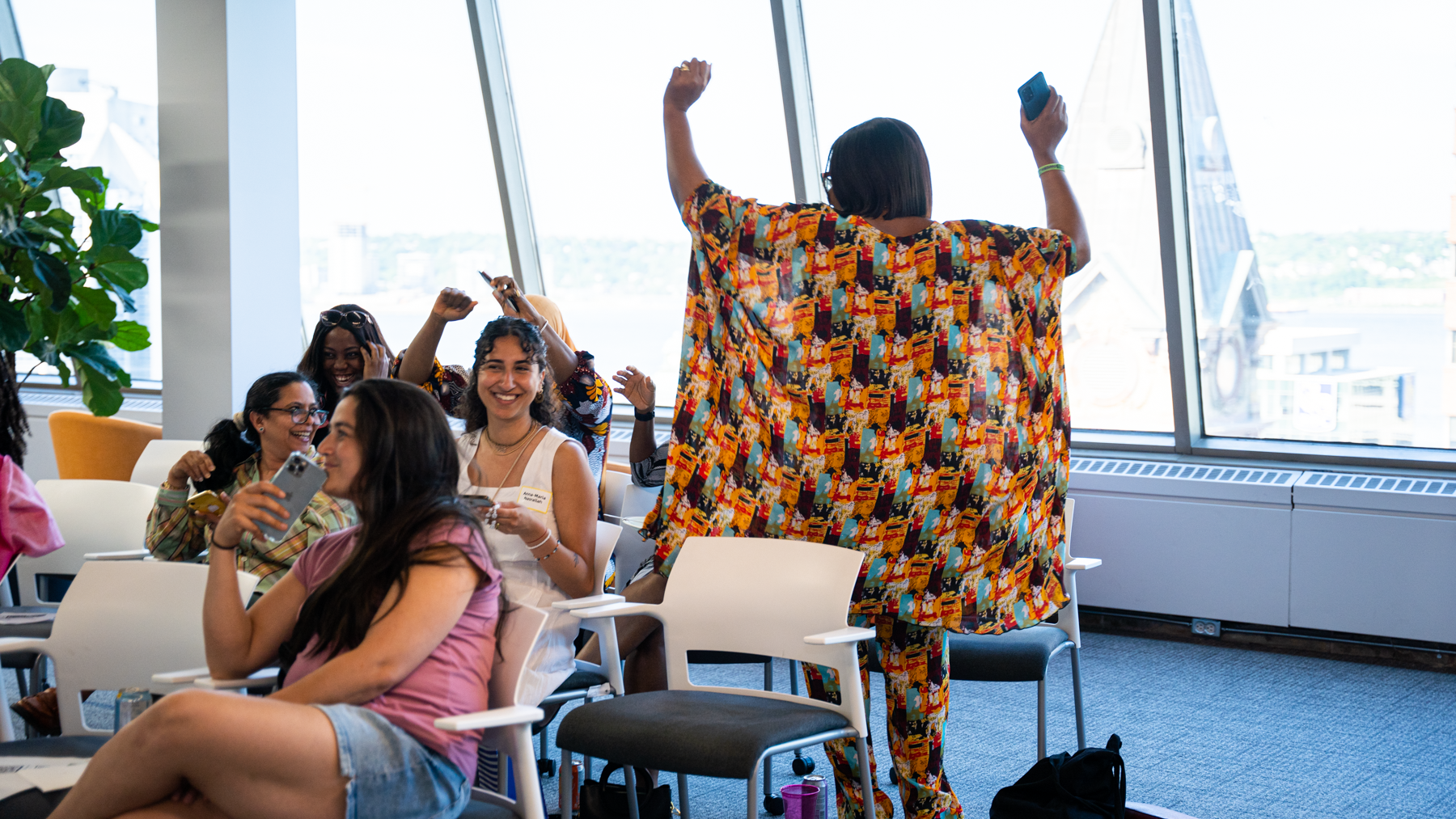 Image of a lady standing up with her hands above her head, celebrating because she won a round of trivia at our 2024 June Connector