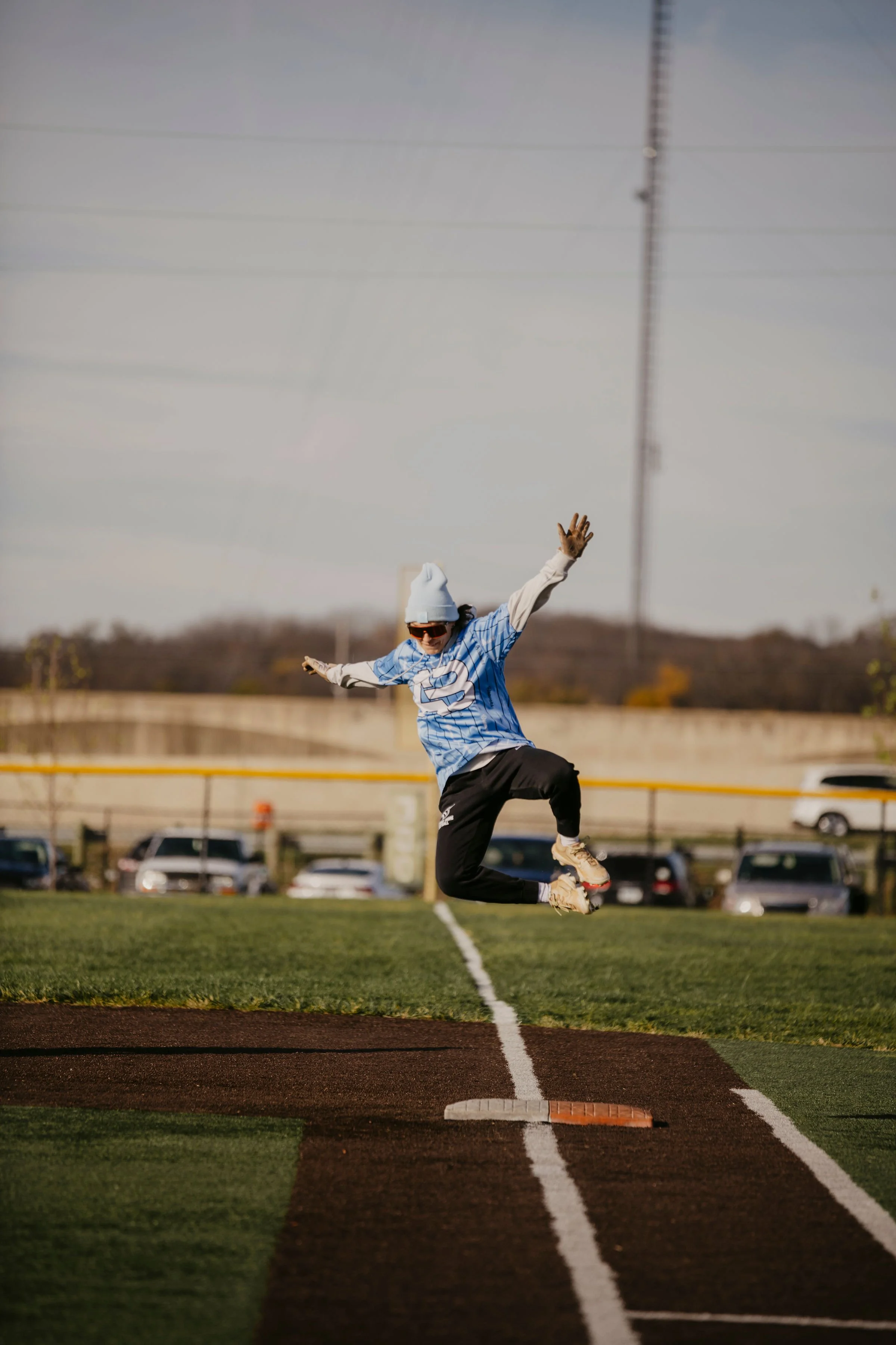 Person jumping in the air on a baseball diamond, at home plate.