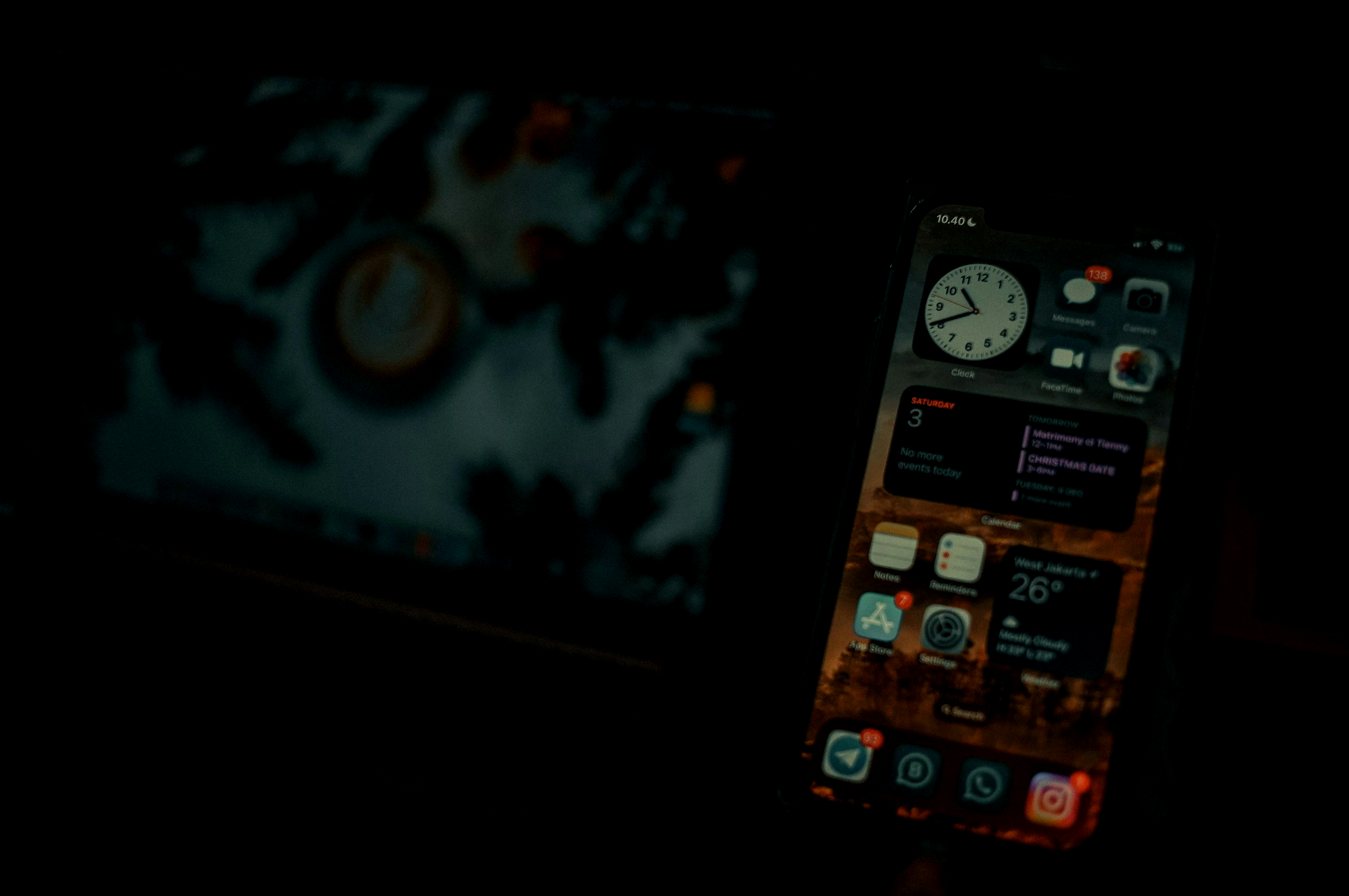 Smartphone displaying various apps and programs icons and widgets in a dark environment.